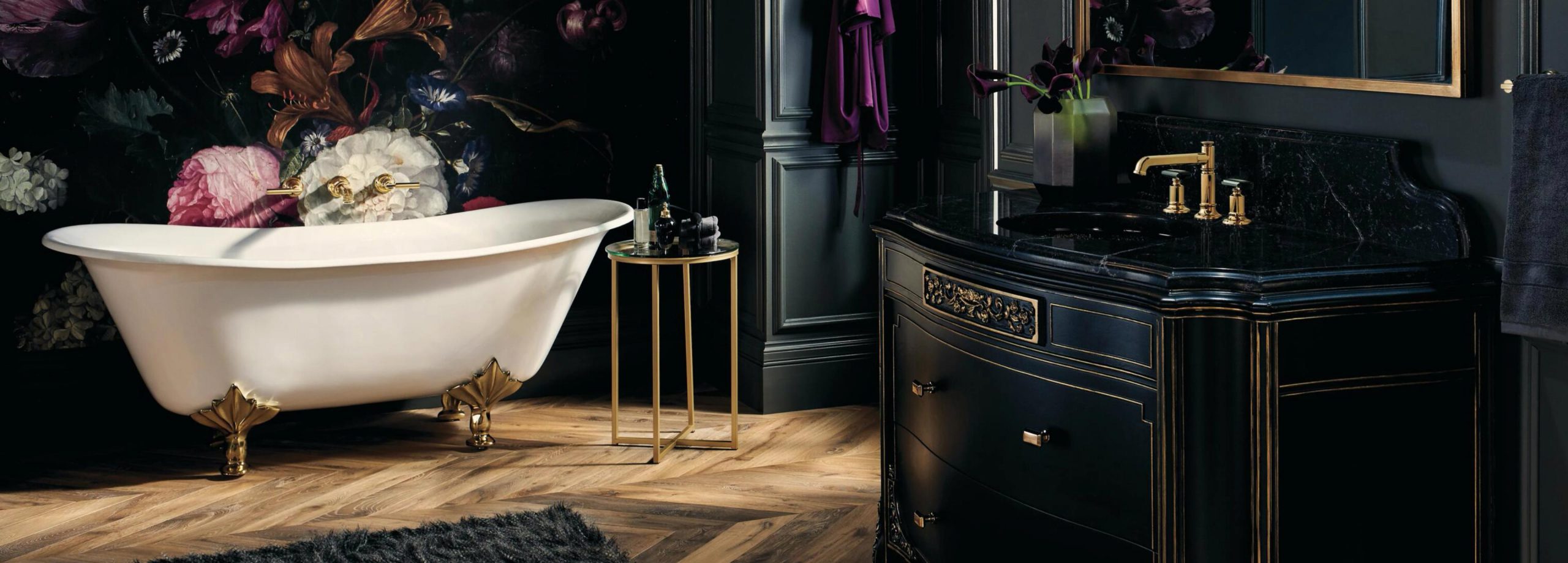 A classic bathroom with dark furniture and features, a wood floor, and a white clawfoot bathtub