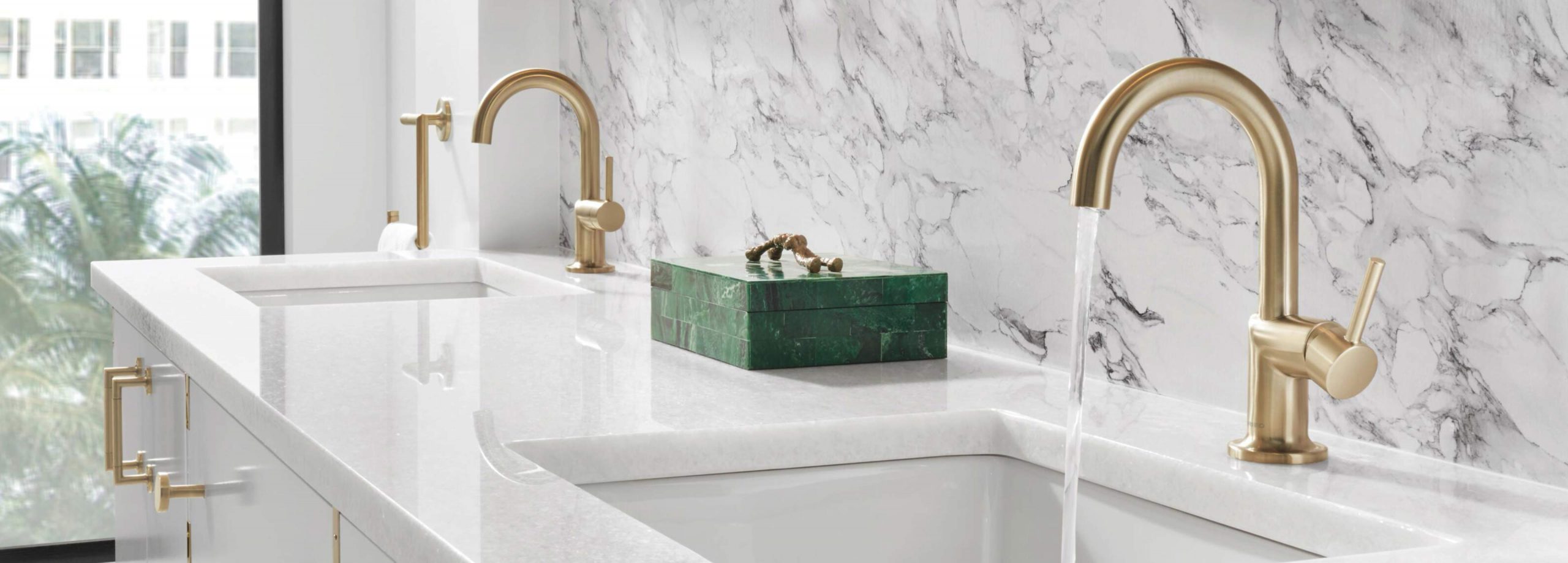 A modern large bathroom with white marble granite and a double vanity with gold plated fixtures