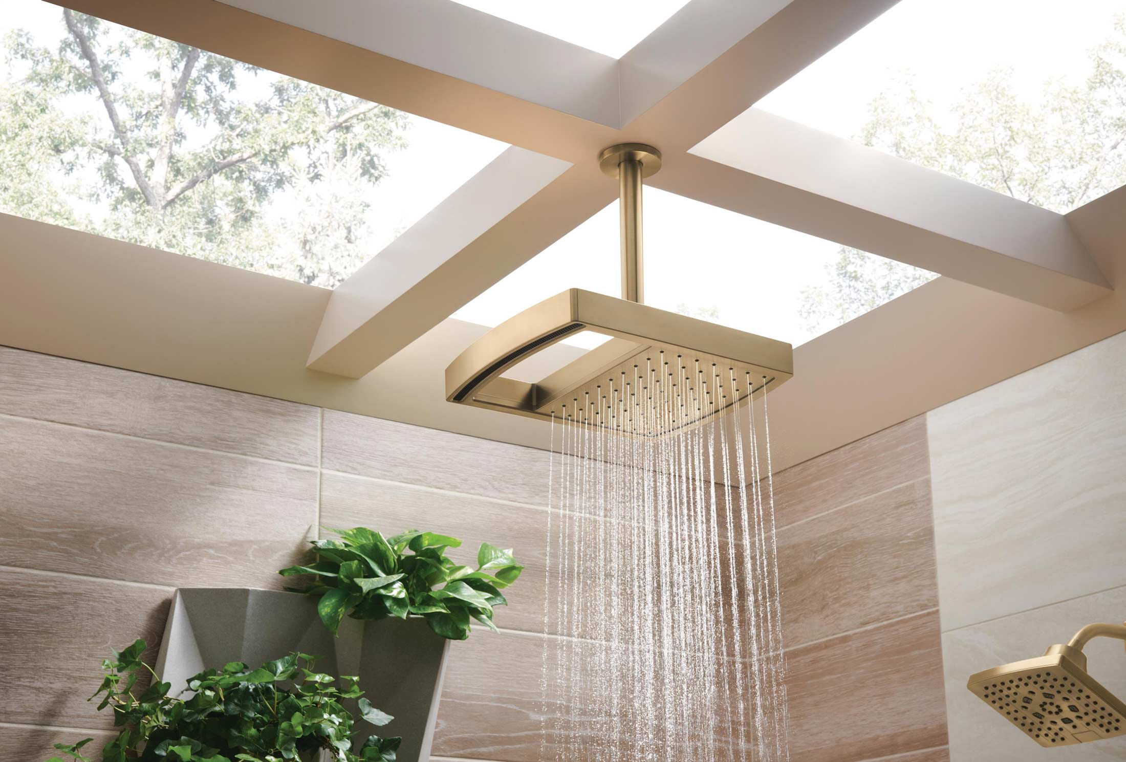 A gold trimmed rainfall shower on the ceiling of an open roof bathroom